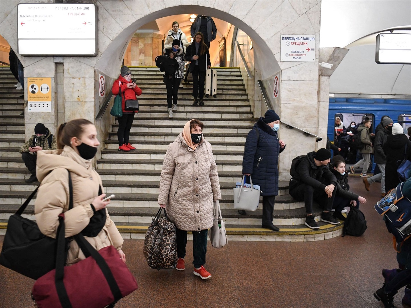 People, some carrying bags and suitcases, walk in a metro station in Kyiv early on February 24, 2022. Air raid sirens rang out in downtown Kyiv today as cities across Ukraine were hit with what Ukrainian officials said were Russian missile strikes and artillery.