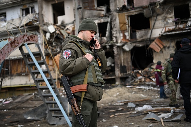 A Ukrainian serviceman in front of a damaged residential building at Koshytsa Street, a suburb of the Ukrainian capital Kyiv.