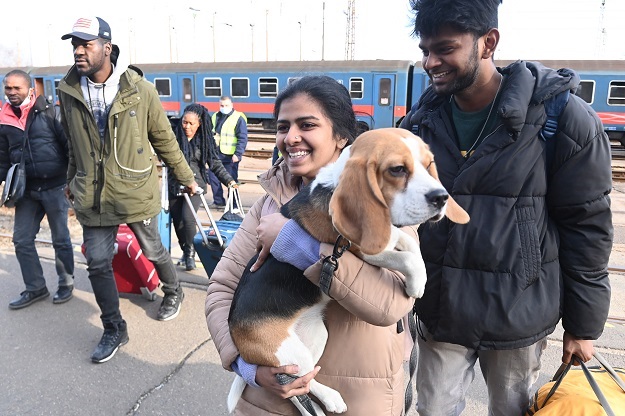 A woman carries her dog as refugees arrive from Uk