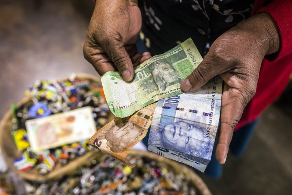 A vendor counts out banknotes while working in an African craft market in South Africa. 