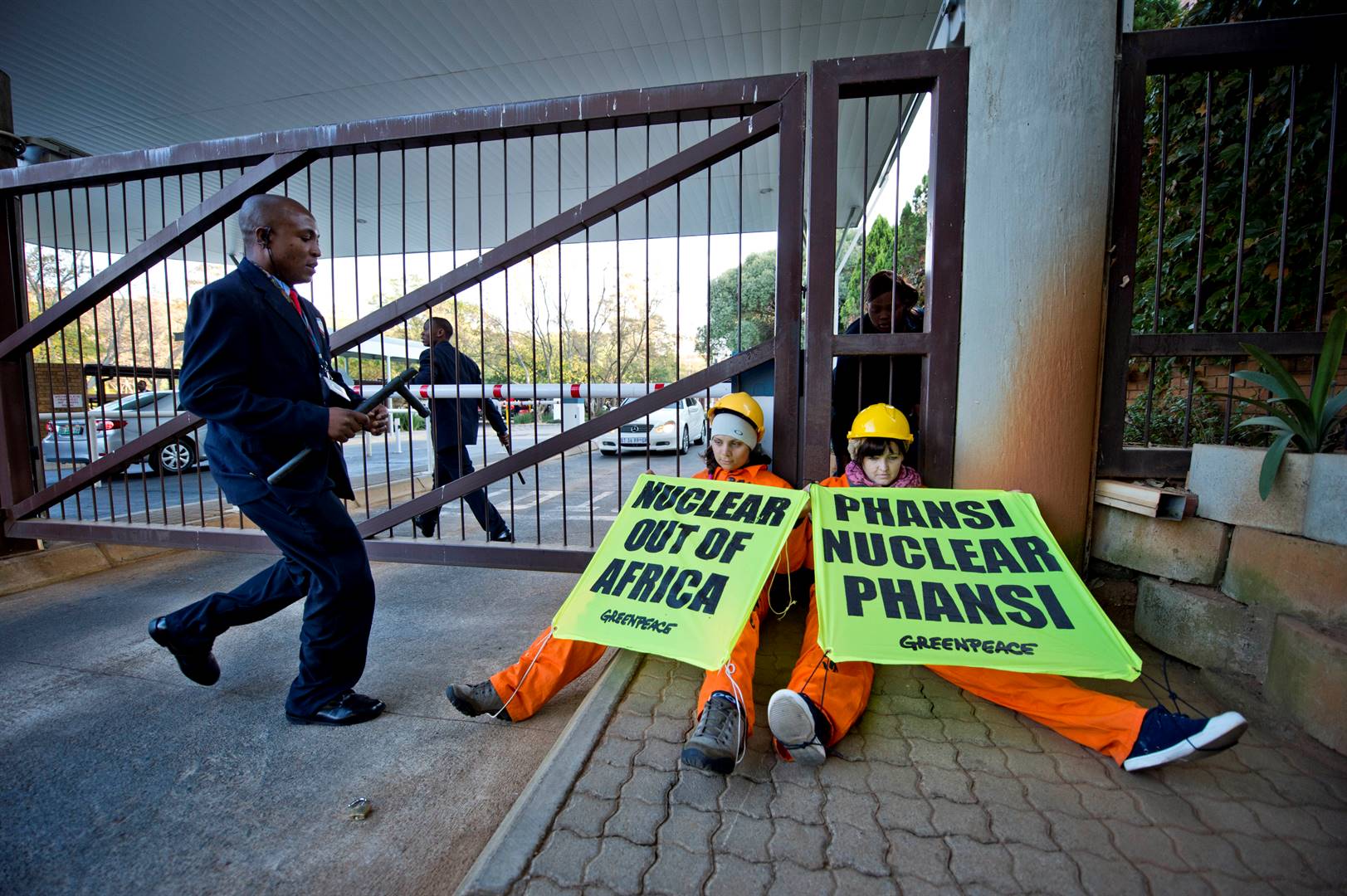 ’n Veiligheidswag sak toe op betogers teen kernkrag in dié argieffoto van ’n protesoptrede in 2005 deur Greenpeace by die kantore van die Nywerheidsontwikkelingskorporasie in Johannesburg. Foto: Cornél van Heerden