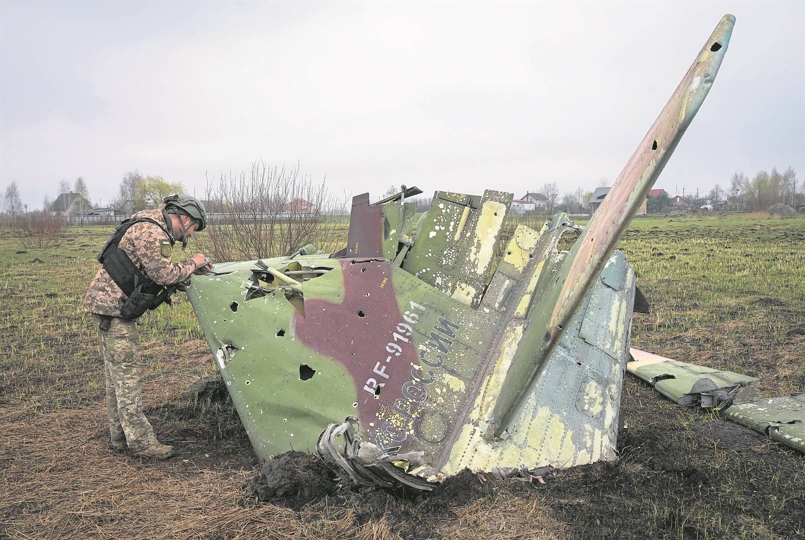 ’n Oekraïense soldaat bekyk die wrakstukke van ’n Russiese veg-vliegtuig wat afgeskiet is. Foto: AP