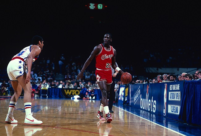  CIRCA 1985: Michael Jordan #23 of the Chicago Bulls dribbles the ball up court guarded by Jeff Malone #24 of the Washington Bullets during an NBA basketball game.
