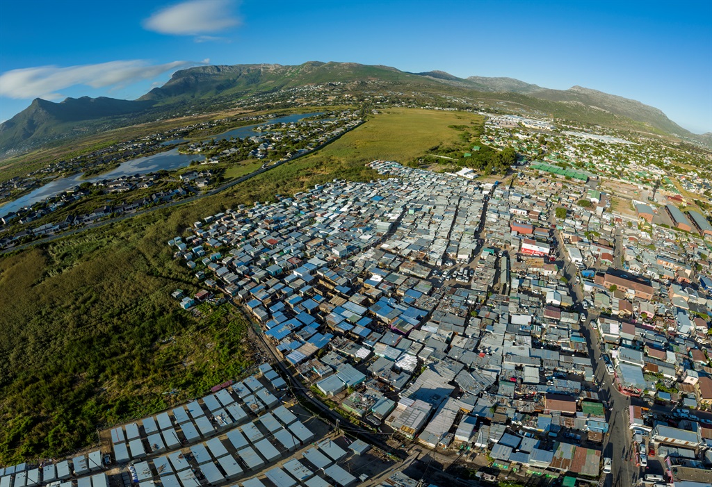 Aerial view of the Masiphumelele informal settlement squatter camp right next to middle class suburban housing Lake Michelle,Cape Town, South Africa. 