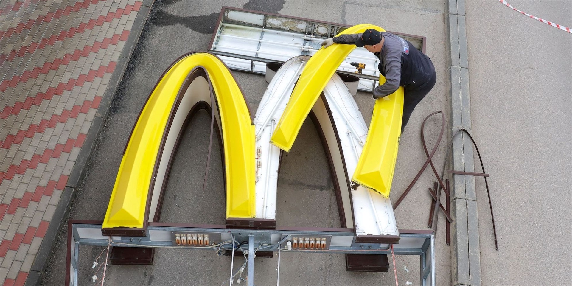 A worker dismantles the McDonald's Golden Arches logo at a drive-through restaurant in Kingisepp, Russia. REUTERS/Anton Vaganov