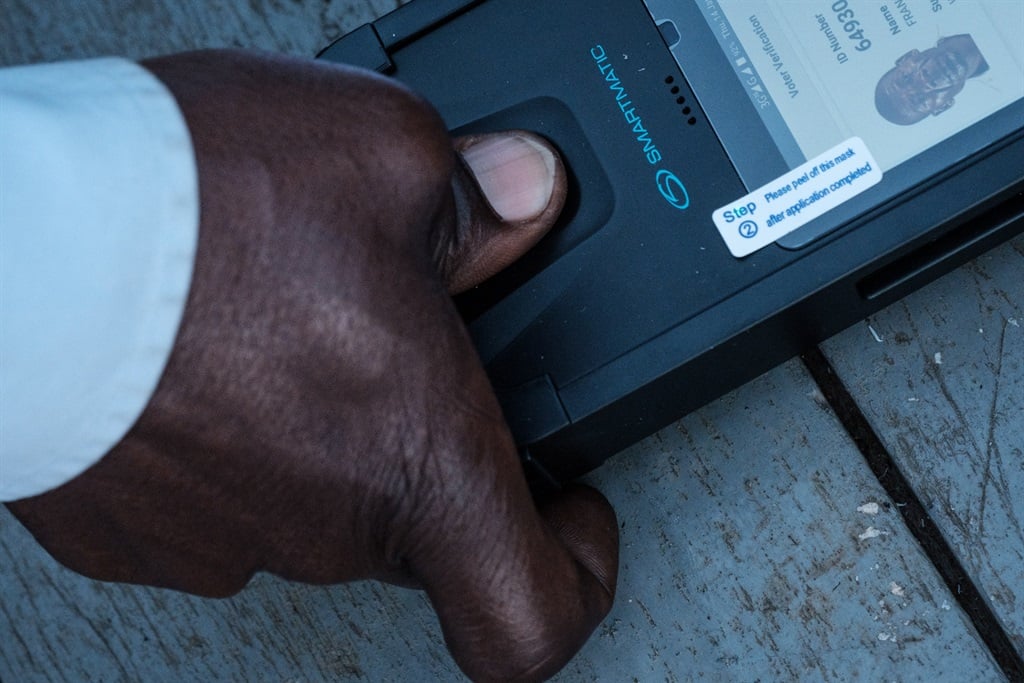 A man puts his thumb on a biometric machine to check his ID to cast his vote at a polling station in Kampala, Uganda, on January 14, 2021.