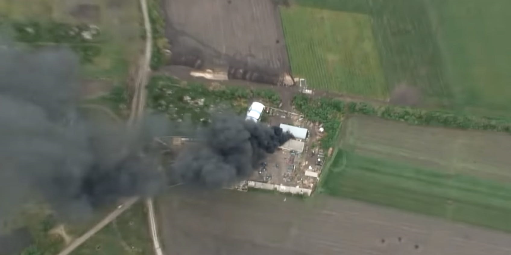 An aerial video still from the Ukrainian army showing a dark plume of smoke coming from a rural building. It has been identified as being in Kharkiv Oblast.