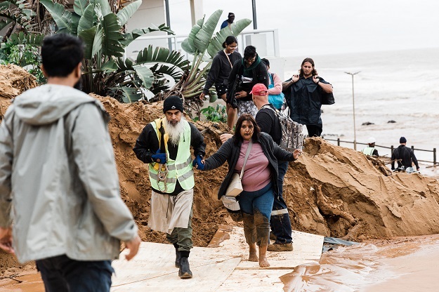 Search and Rescue teams assist local residents to safety following heavy rains and winds in Umdloti north of Durban.