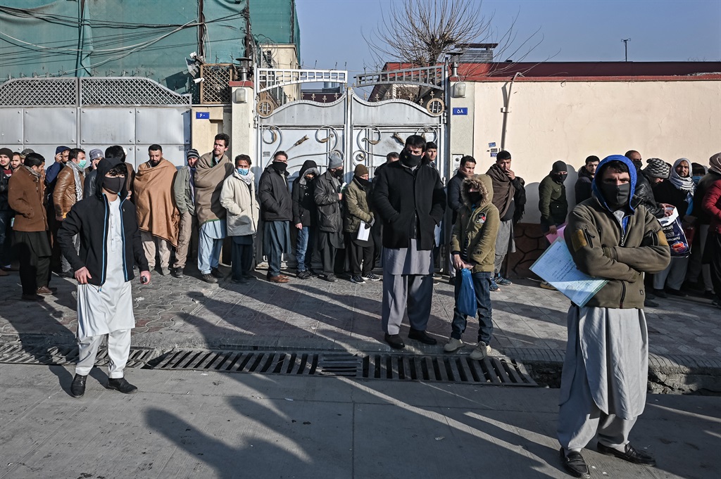 People queue to enter the passport office at a checkpoint in Kabul on 19 December 2021, after Afghanistan's Taliban authorities said they will resume issuing passports.