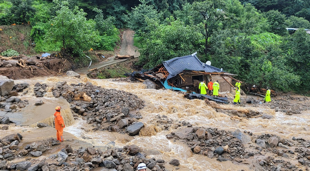 This handout photo taken and released on July 15, 2023 by the Gyeongbuk Fire Service Headquarters shows South Korean emergency workers searching for survivors at a house destroyed by flood waters after heavy rains in Yecheon.