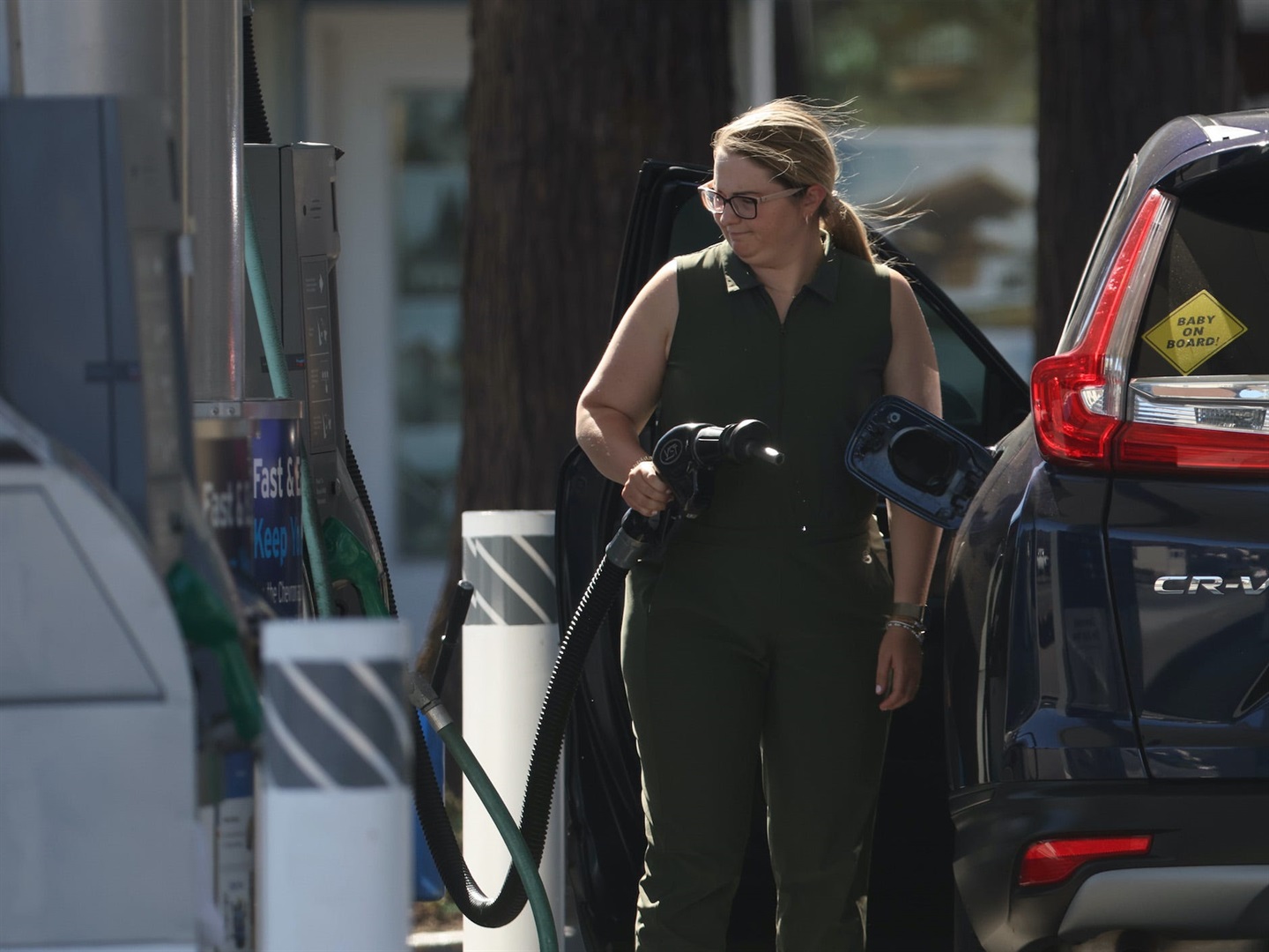A woman putting petrol into a car at a forecourt station.