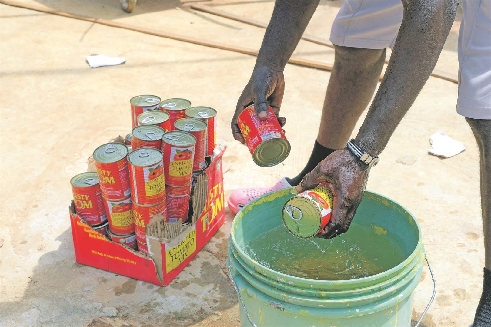 A worker washes salvaged cans of tomato paste at a Food For All Africa warehouse. Photo: Francis Kokoroko