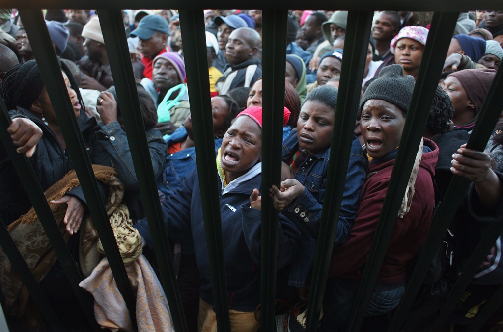 Illegal Immigrants, most of them from Zimbabwe, are smashed against a fence at the entrance of a refugee centre June 17, 2008, in Johannesburg, South Africa. In 2008, with the economic collapse of Zimbabwe and widespread political oppression, more than 3 million Zimbabweans flooded across the border into South Africa.  (Photo by John Moore/Getty Images)