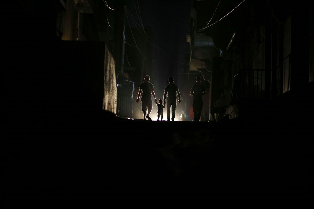 Palestinians walk on a street in Al Shateaa refugee camp during a power outage in Gaza City, Gaza Strip in this file picture. 