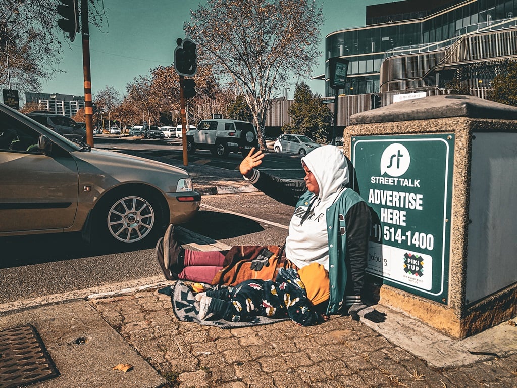 A mother waves her hand to a motorist at one of the intersections in Sandton, Johannesburg.