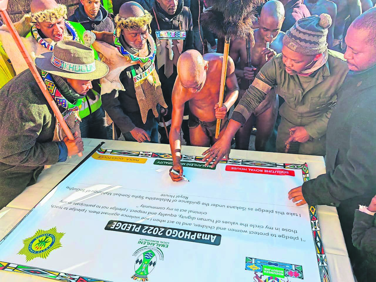 Left: A Ndebele initiate of the SoGutjhe Royal House in Phola Location in Mpumalanga signs a pledge against gender-based violence.    Right: Ikosi Sipho Mahlangu (front, third from left) surrounded members from his royal house holding the initiates’ signed pledge. 