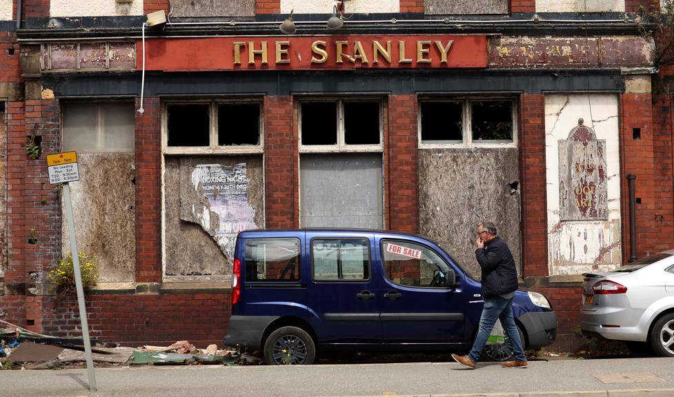 ’n Man stap verby ’n vervalle kroeg in Liverpool. Foto: Reuters