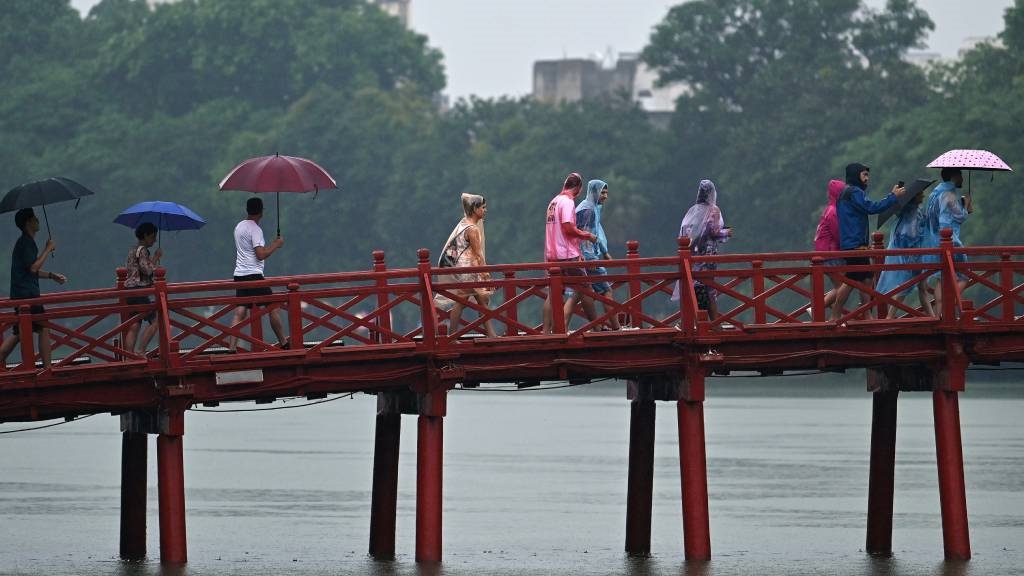 Tourists walk over Huc Bridge on Hoan Kiem Lake in