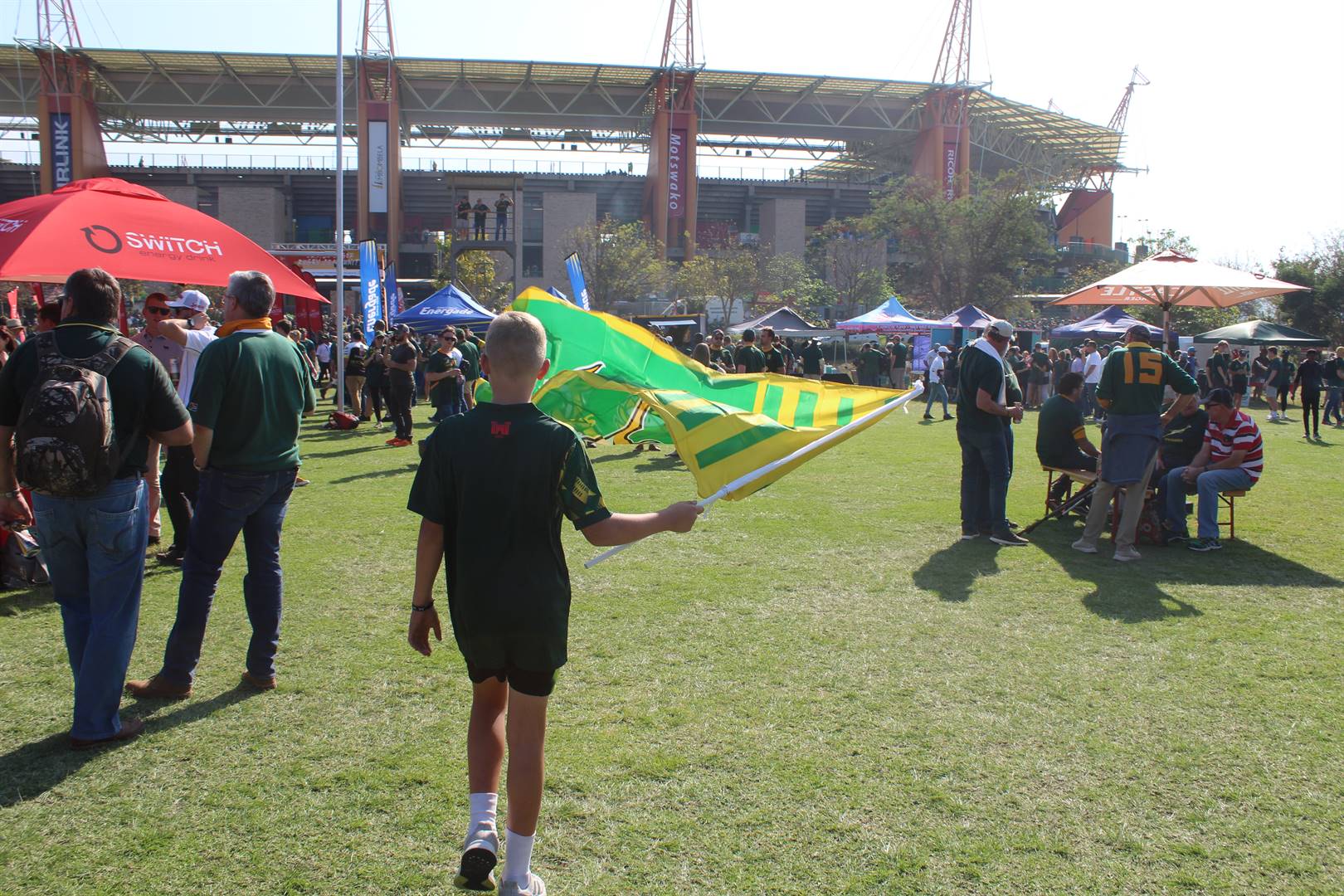 ’n Jong ondersteuner swaai sy vlag buite die Mbombela-stadion. Foto: Arisa Schamrel