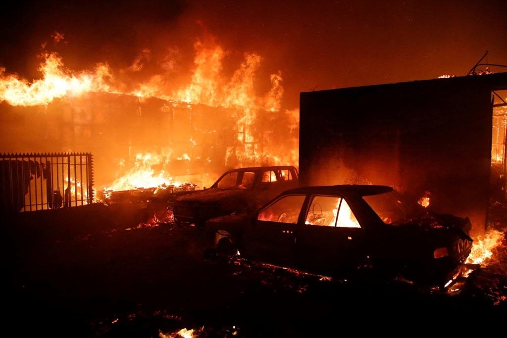 Vehicles and homes burn during a fire in Viña del Mar, Chile, on February 2, 2024. A huge mushroom cloud of smoke hangs over tourist areas in central Chile, including Viña del Mar and Valparaiso, where a forest fire broke out on Friday, threatening hundreds of homes and forcing the evacuation of residents. 