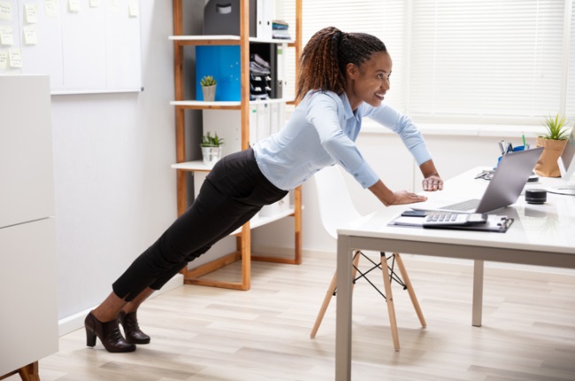 A businesswoman doing push-ups using her office desk. Studies show that even our mental firepower is linked to how physically active we are.