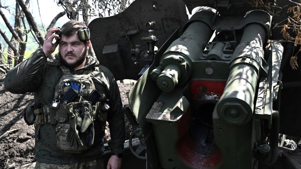 A Ukrainian artilleryman stands next to a 152mm to