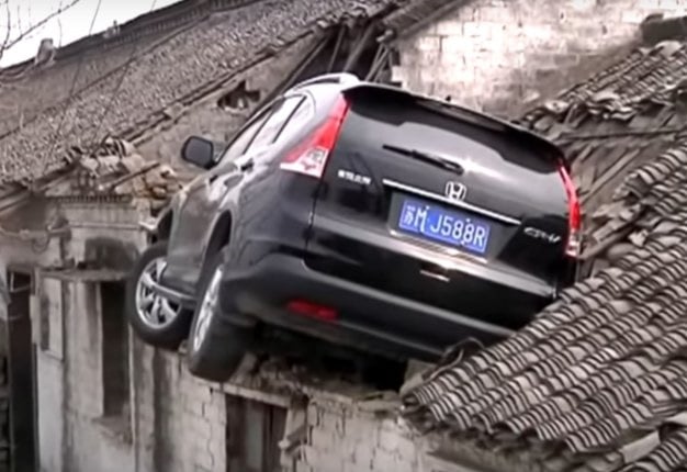 <b>WHAT A CRASH:</b> CCTV footage captures the moment a driver accidentally hits the accelerator of his SUV instead of braking and ends up landing on a rooftop <i>Image: YouTube</i>