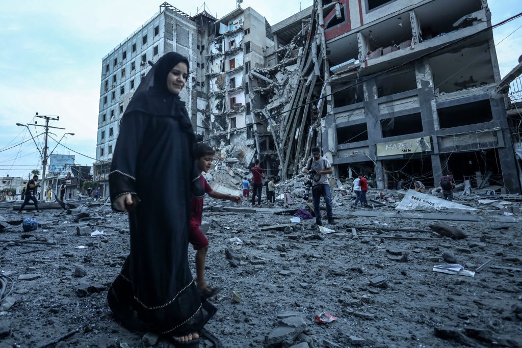 Palestinians walk in front of the rubble of a destroyed building in Gaza.