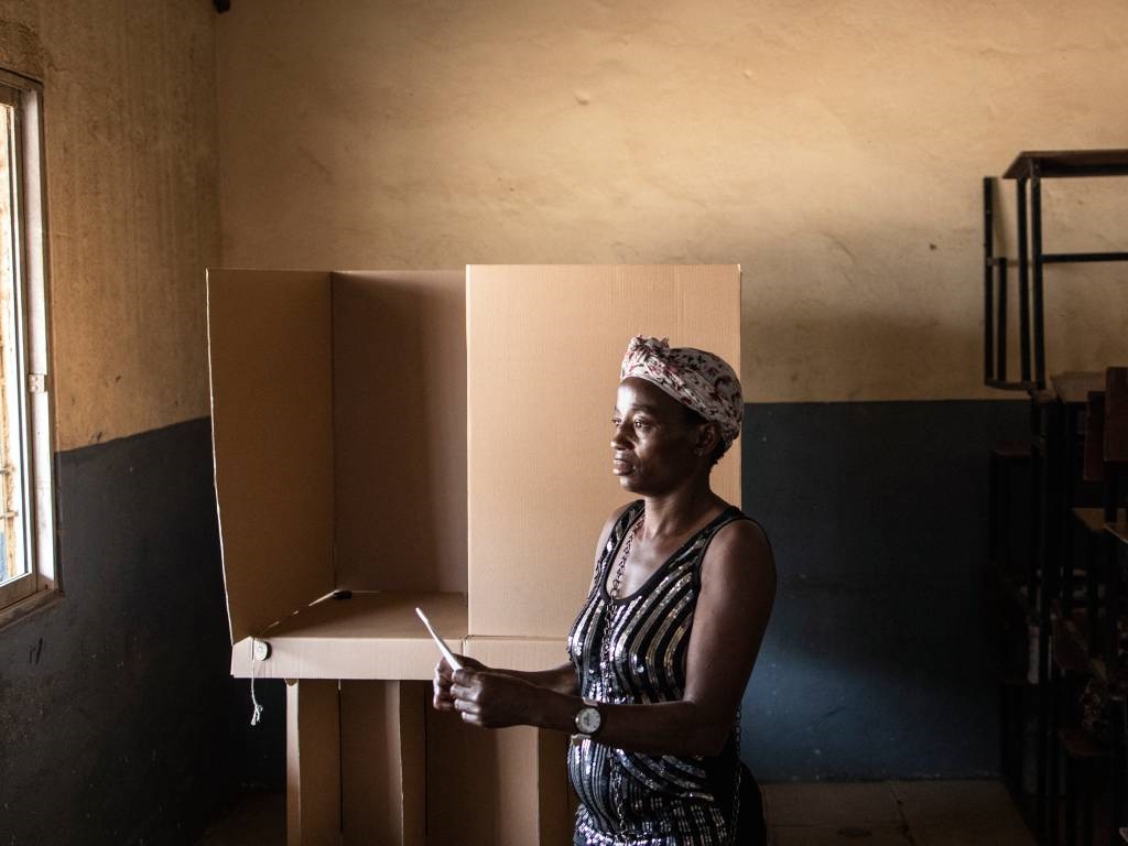 A woman folds her ballot paper at a voting booth i