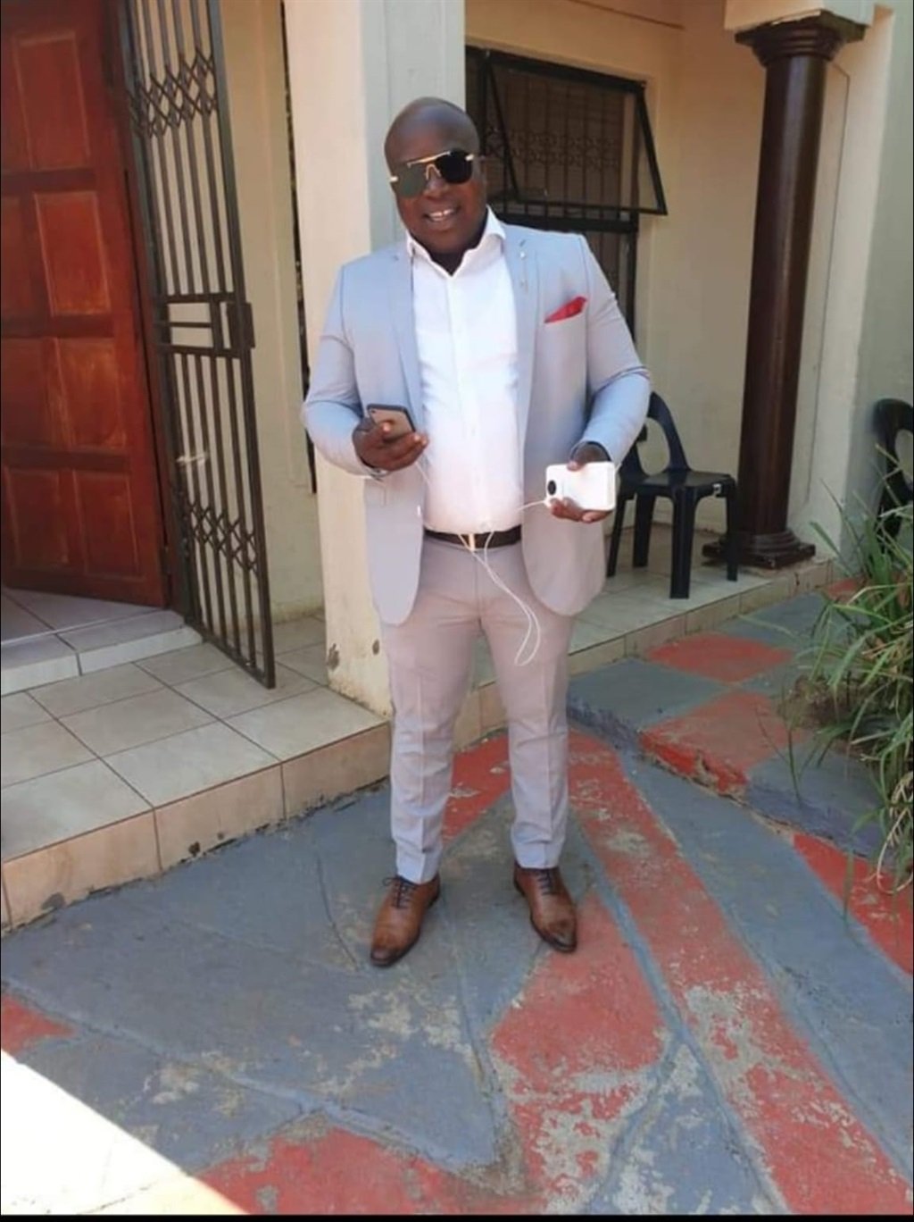 Sello Sekhokho seen posing in suit outside house