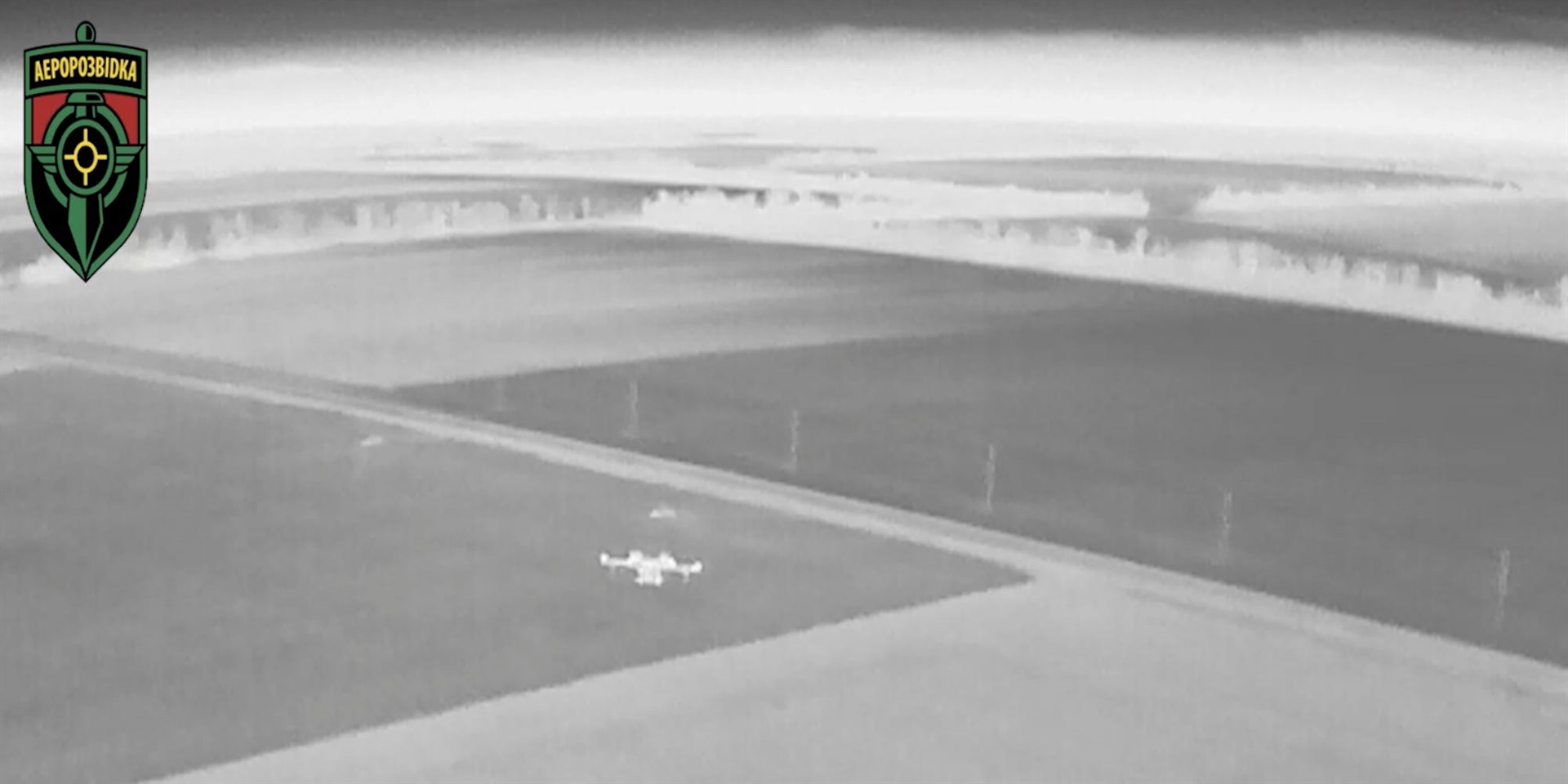 A black and white night view from an Aerorozvidka drone showing another drone in operation in Ukraine.