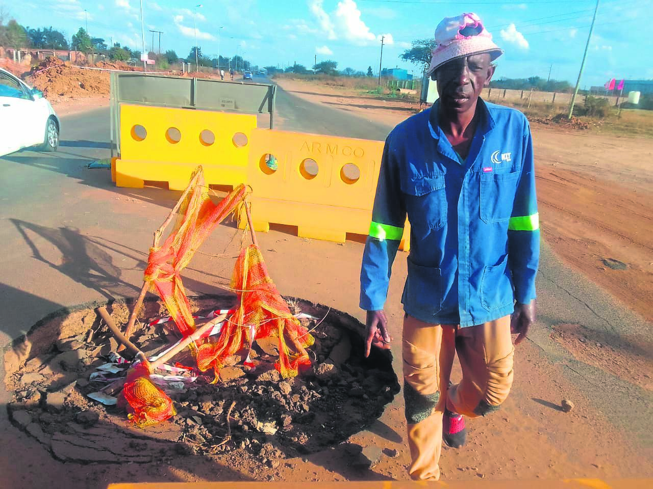 Dick Mathebula of Ramotse in Hammanskraal directs motorists not to drive into this huge pothole in his kasi.                         Photo by Raymond Morare