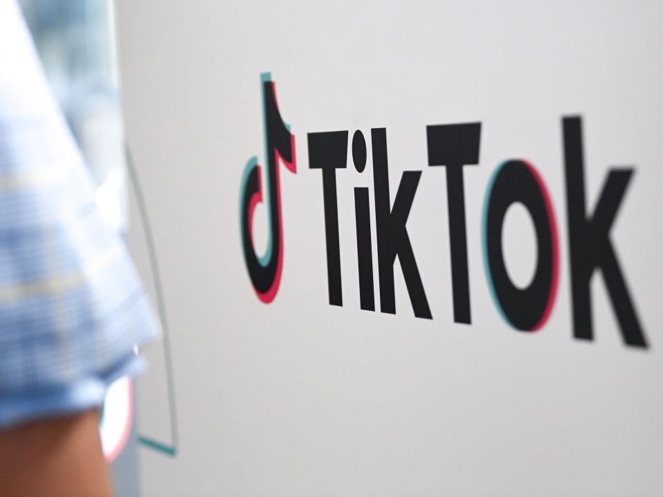 A person walks past a sign for TikTok.