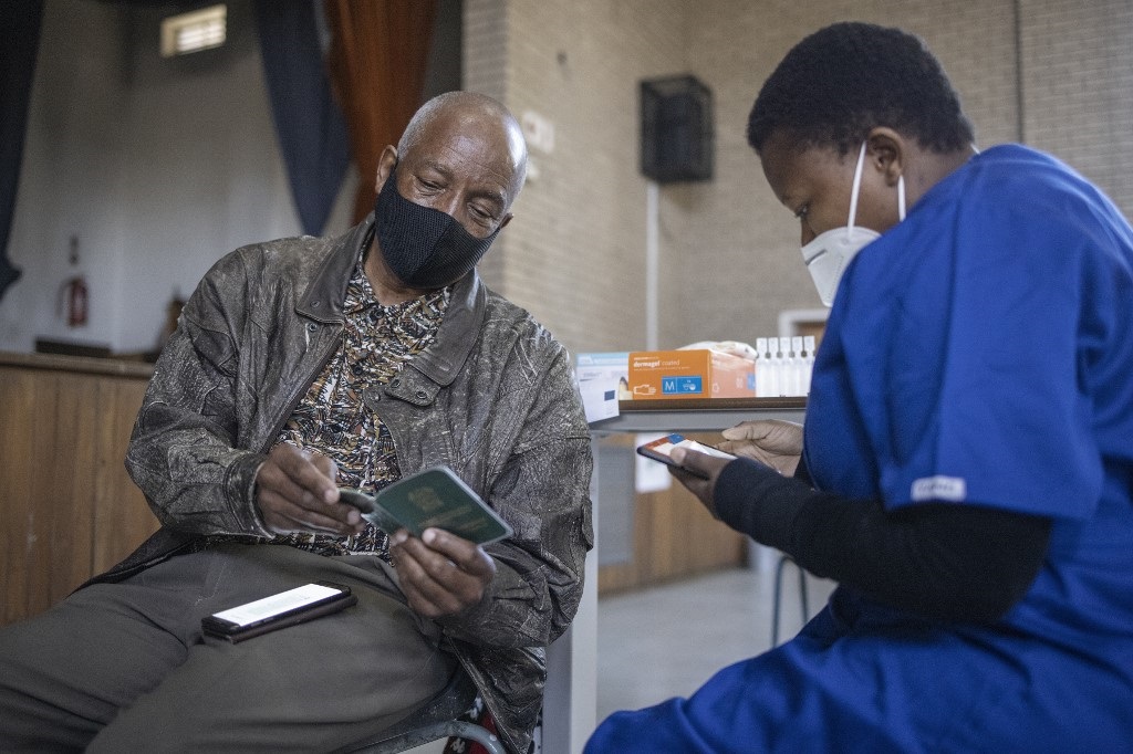 A health care worker register an elderly man ahead of vaccinating him with Pfizer vaccines at the Bertha Gxowa Hospital in Germiston.