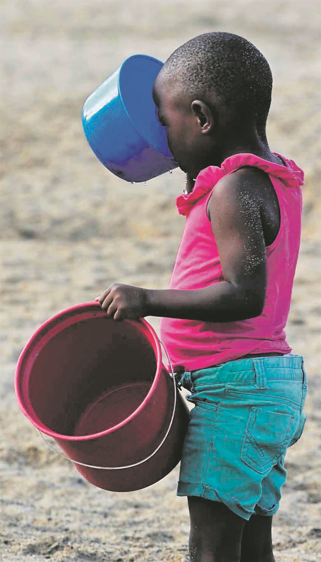 A child takes a sip of water from a hole she dug in the river. Picture: Tebogo Letsie 