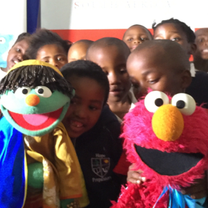 Neno and Raya of Takalani Sesame celebrating the launch of new educational resources with Hope School children at Johnson & Johnson in East London.