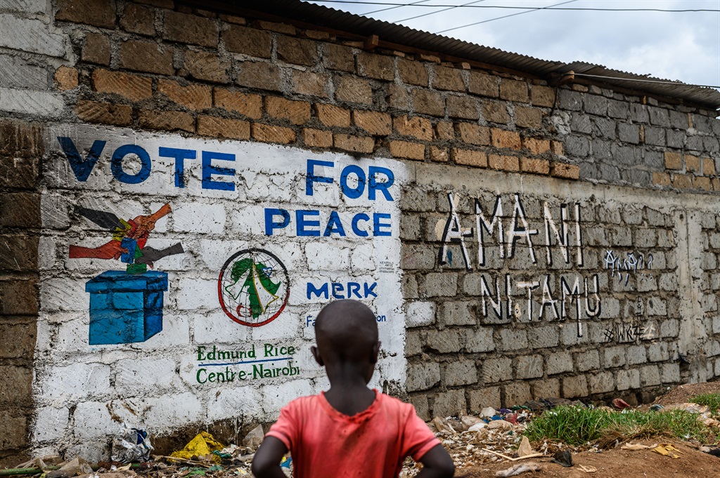 A boy looks at a mural done by the Art360kibera collective, promoting a message of 'Vote for Peace', in Kibera on August 8, 2022, ahead of Kenya's general election.