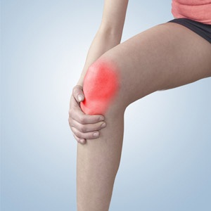 Woman holding hand to spot of knee-aches.