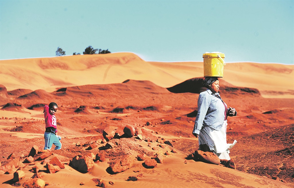BATTLEGROUND Mablasi Yalo (67) and her granddaughter, four-year-old Azola, walk along the red dunes in Xolobeni near Mbizana in the Eastern Cape. Picture: Leon Sadiki 