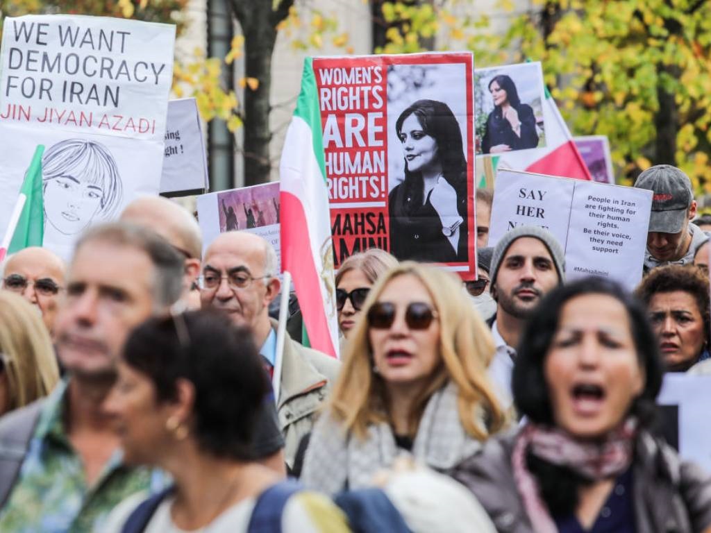 Demonstrators, some hold banners with the image of Mahsa Amini and Shah-era flags, march in solidarity with protesters in Iran.