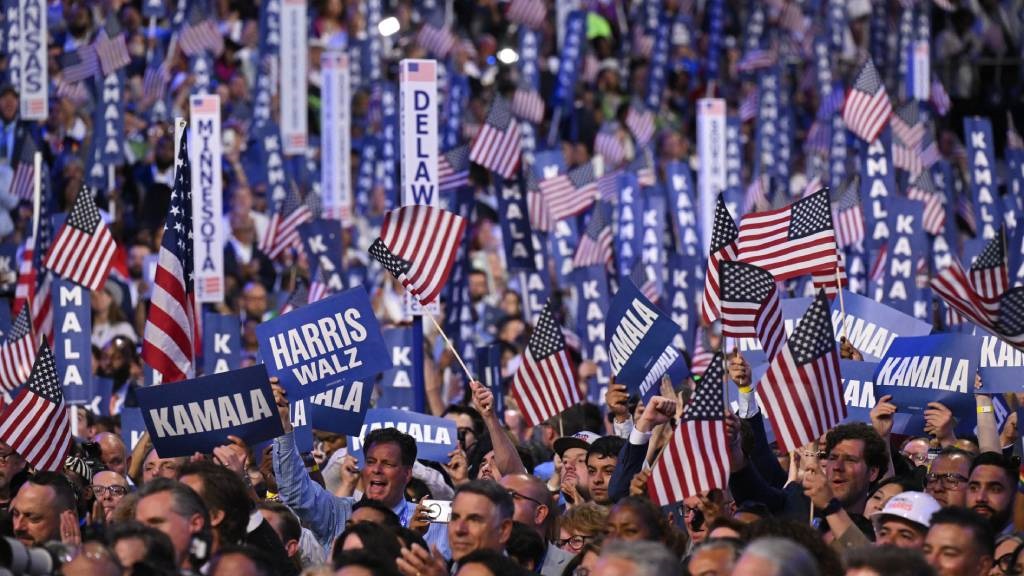 Delegates hold signs and wave US flags on the four