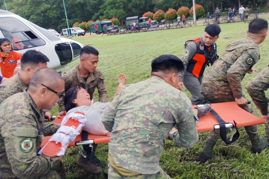 Philippine soldiers transferring a landslide survivor from a helicopter to an ambulance following a medical evacuation flight from Maco to the Davao Regional Medical Center in Tagum, Davao del Norte province.
