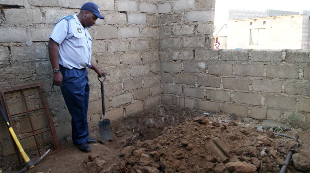 GRISLY FIND: Lieutenant Mzwandile Nyambi looks into the shallow grave where a woman’s body was found. 

Photo by 
Elizabeth Langa