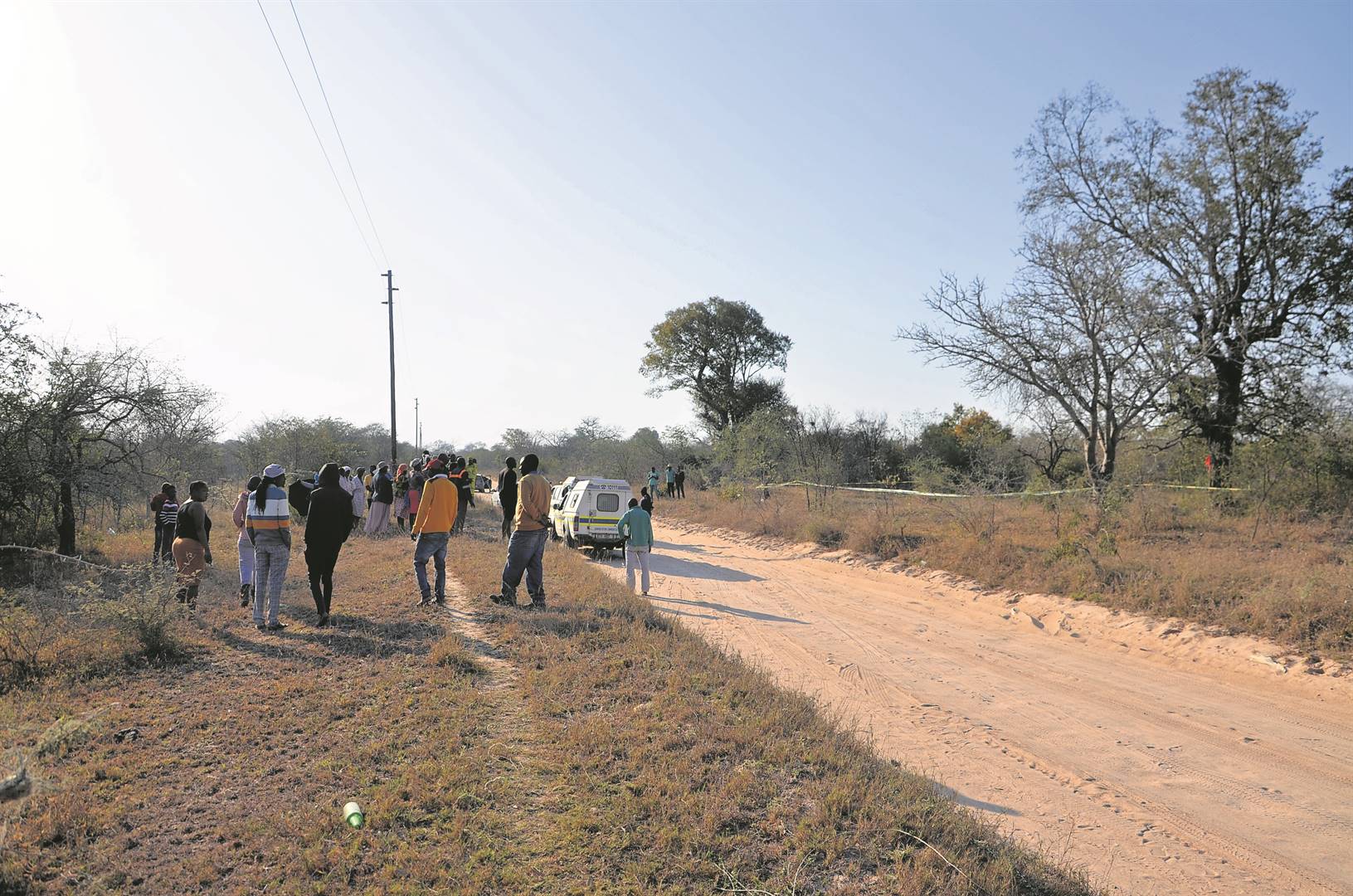 Shocked villagers stand next to the bushes where Domingo Hlungwane’s body was found hanging from a tree.