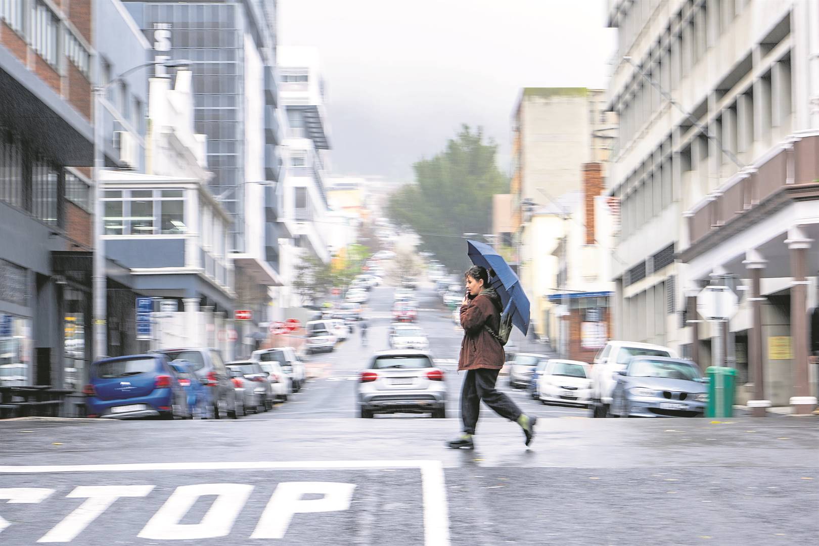 ’n Vrou stap met ’n sambreel in Kaapstad se middestad. Reën kan Maandag en Donderdag in dele van die Suidwes-Kaap uitsak.  Foto: Jaco Marais