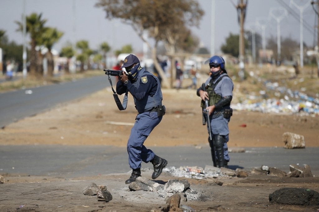 A member of the South African Police Services (SAPS) aim at looters following sporadic looting and vandalism outside the Lotsoho Mall in Katlehong township, East of Johannesburg.