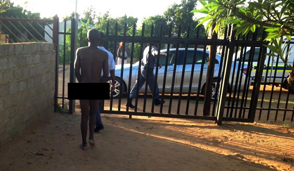 Cops escort the naked man who was found trapped in the Mahlayeye family’s yard in Temba. Photo by Raymond Morare 