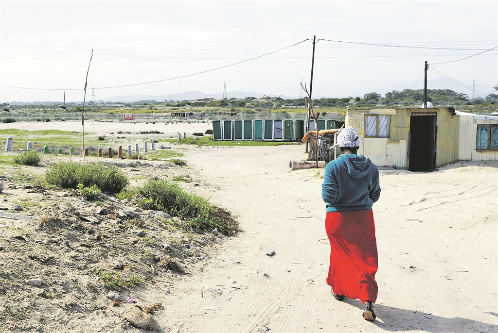 Iminathi Mafevuka walks towards the communal toilets in Blowey, SST, where Sinoxolo Mafevuka, her sister-in-law, was found raped and murdered. Picture: Zingce Gamiso 