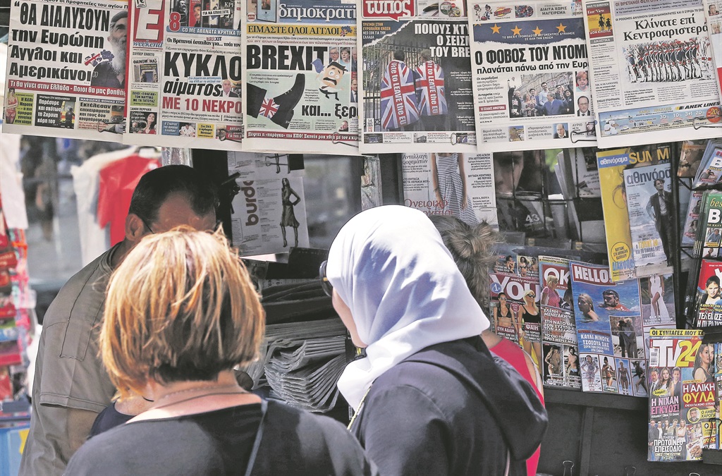 People glance at the front pages of Greek newspapers hanging on a kiosk in central Athens yesterday. Britain’s decision to leave the European Union may hit Greek exports to that country and affect businesses and tourism. However, the size and structure of the Greek economy will shield it from heavier losses, market executives and bankers said on Friday.  PHOTO: EPA 