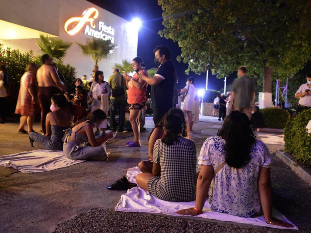 People remain outside a hotel after a quake in Aca